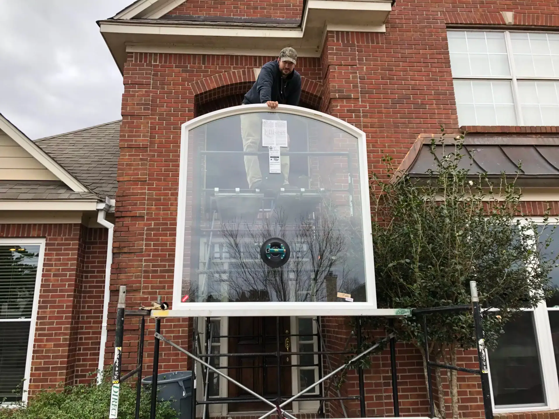 Installer fitting the new arched window on the brick home