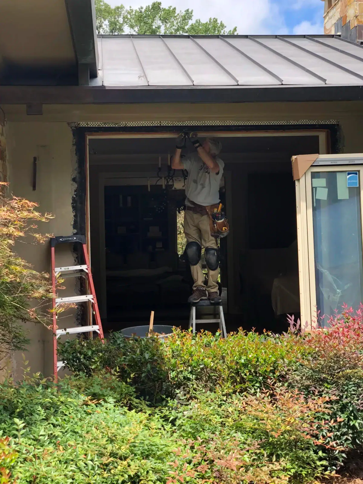 Installer replacing a window on a home with a standing-seam metal roof