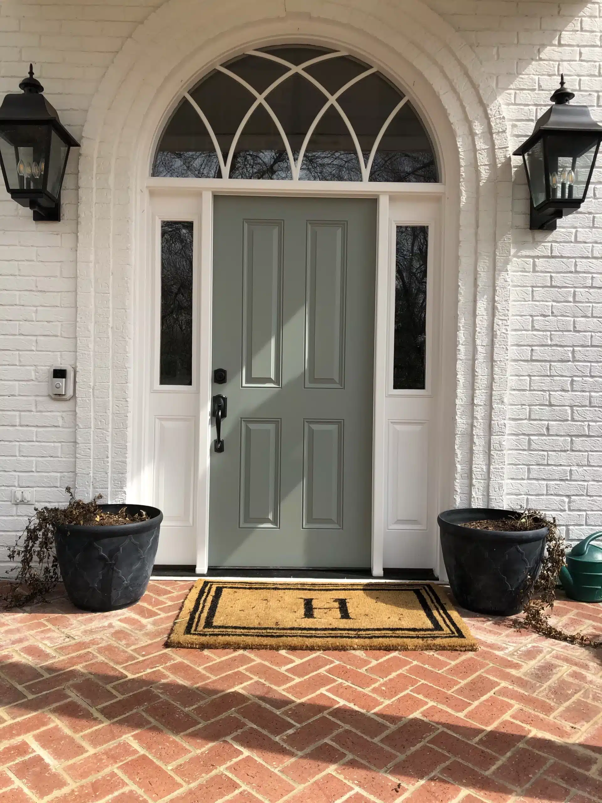 White brick home entry with a new sage-green front door, sidelights and half-round transom